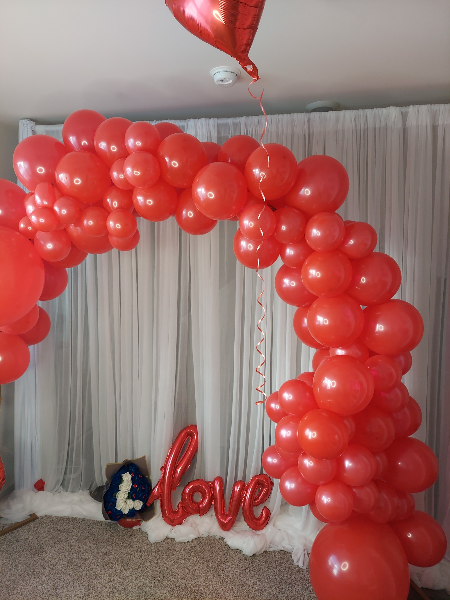 Red balloon arch with white draping and love decoration