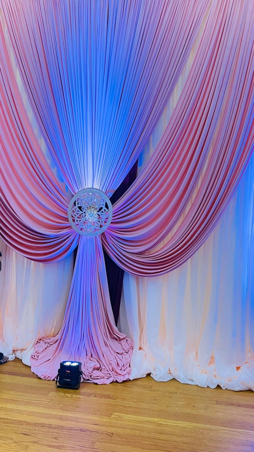 Layered blush and ivory event draping illuminated with blue accent light