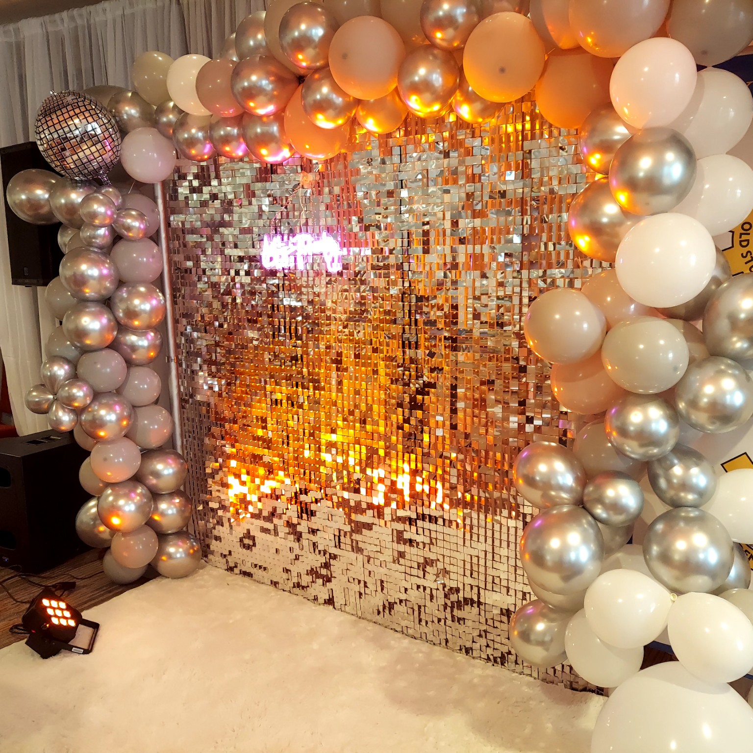 Champagne, silver and white balloon installation framing a shimmering sequin backdrop