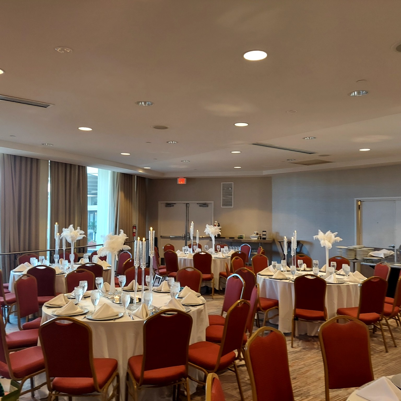 Elegant reception tables arranged with white linens, candlelight and feather centerpieces