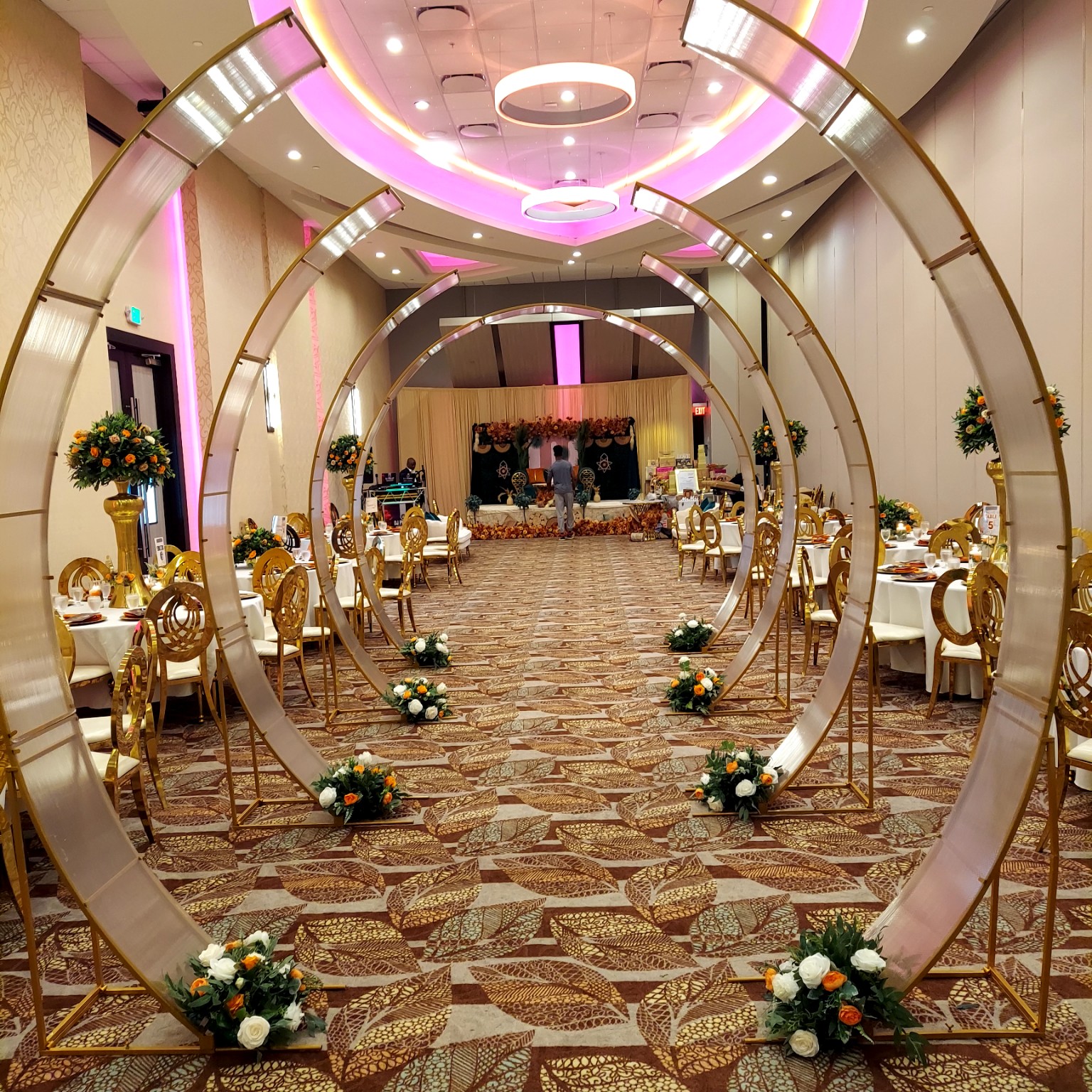 Gold circular entrance arches with floral arrangements leading into an elegant reception